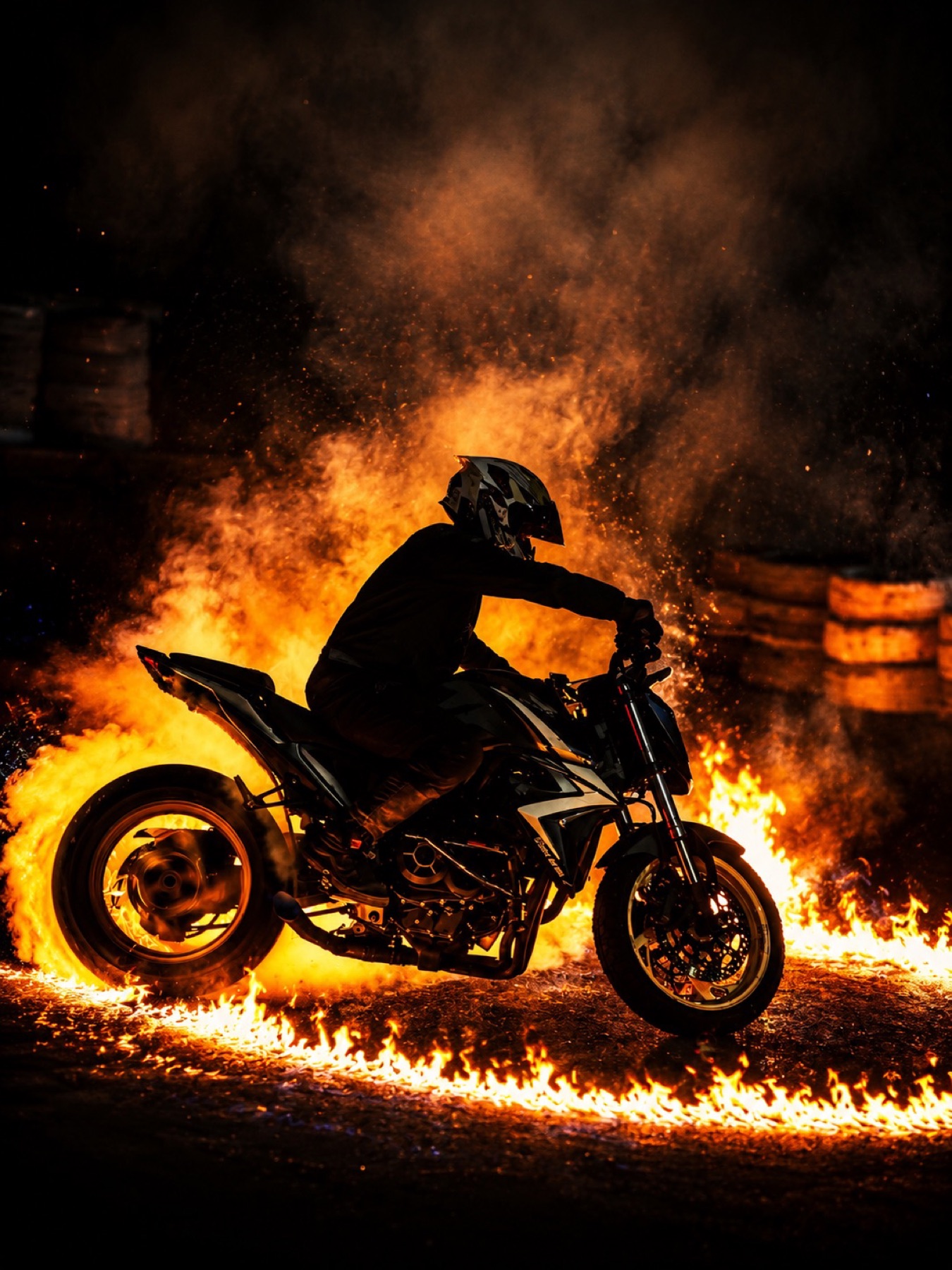 Moto e piloto envolvidos por um anel de fogo à noite