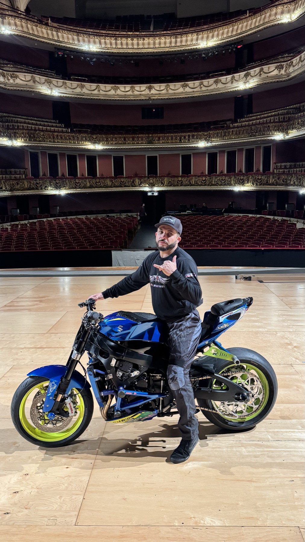 Darlan de pé com a moto no palco vazio do Theatro Municipal