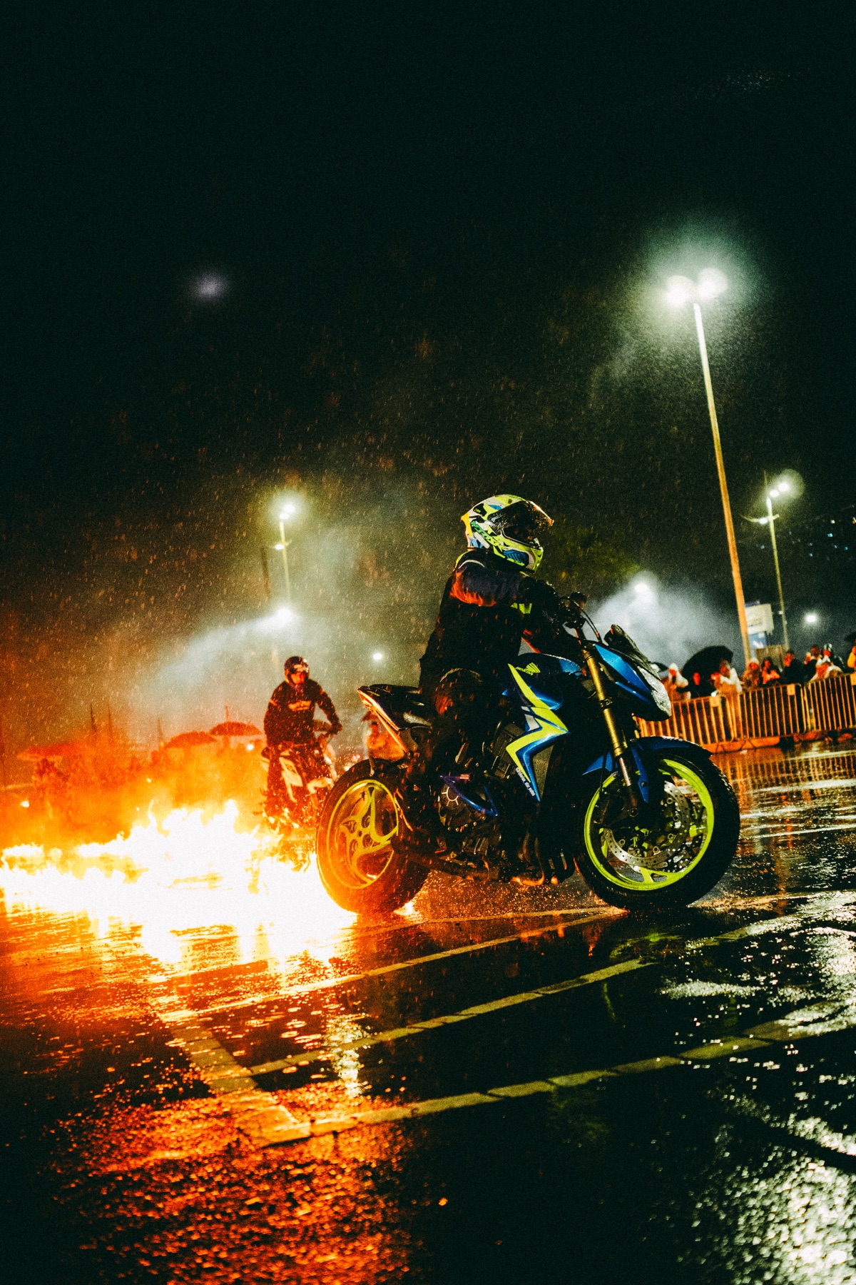 Moto passa por fogo em evento noturno sob refletores