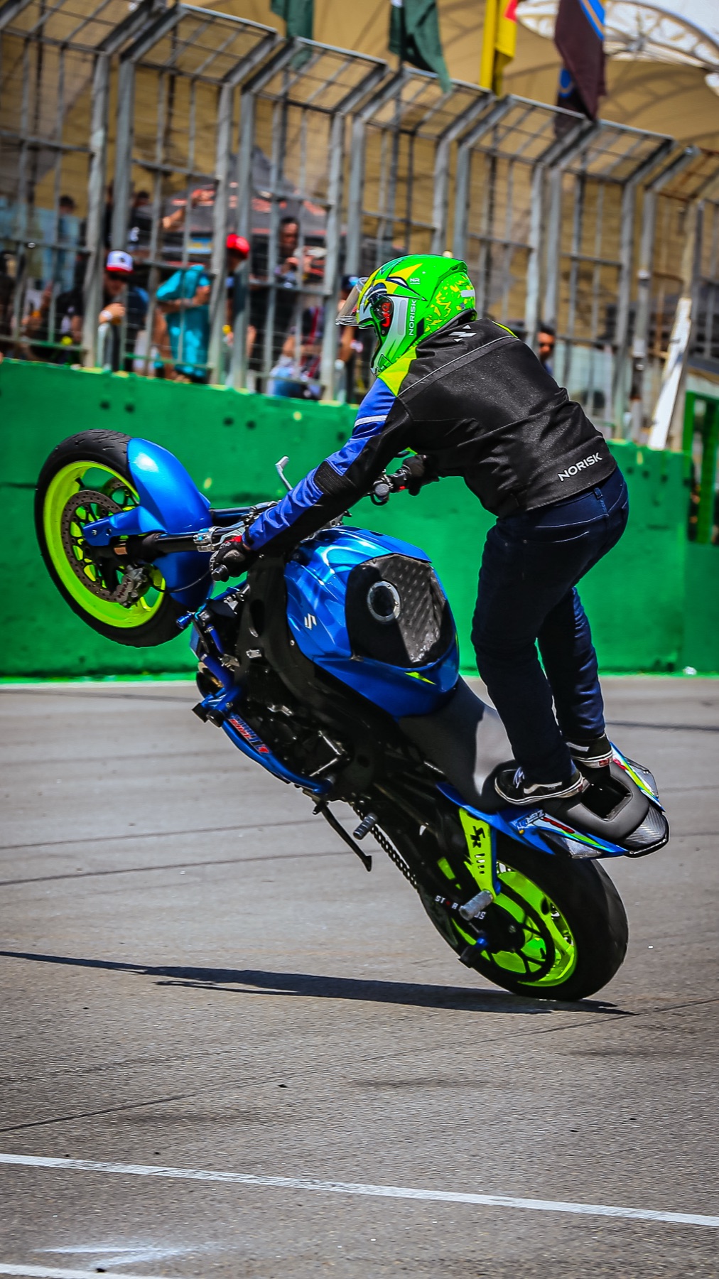 Wheeling em pé com o público ao fundo no autódromo
